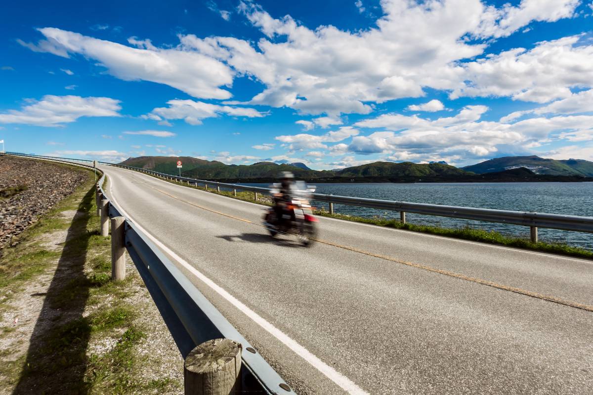 Biker rides a road with Atlantic Road in Norway. Atlantic Ocean Road or the Atlantic Road (Atlanterhavsveien) been awarded the title as "Norwegian Construction of the Century". Biker in motion blur.