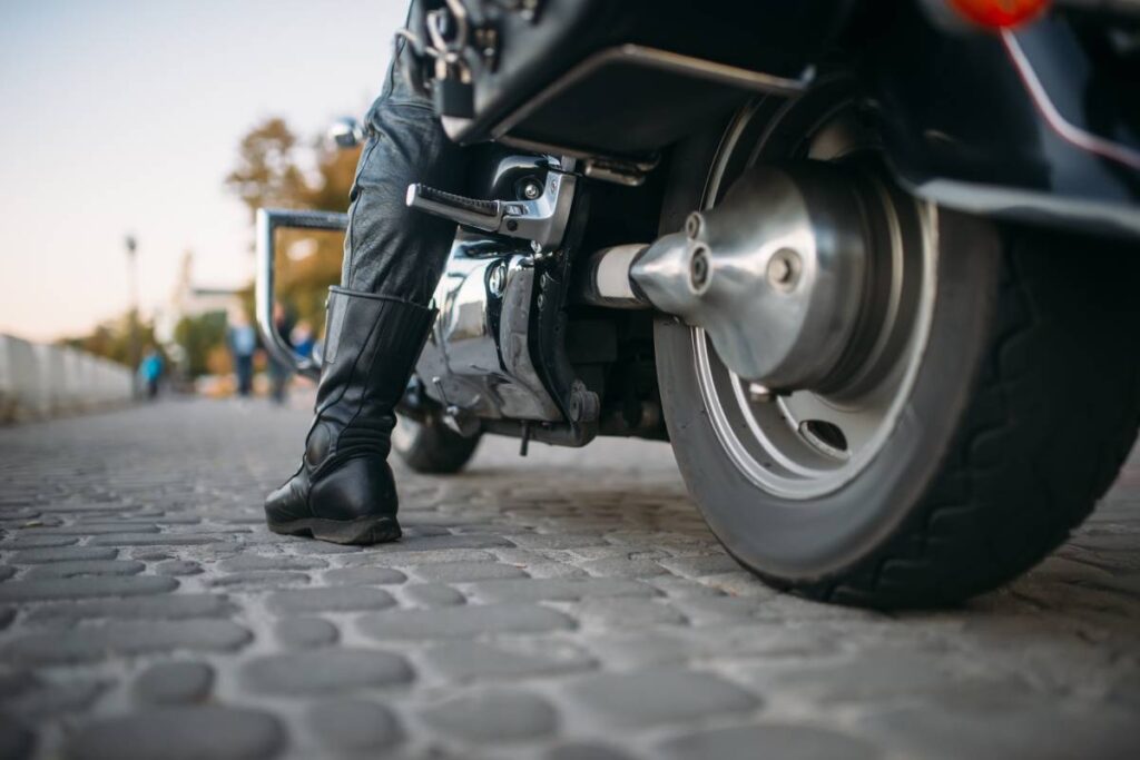 Biker in leather clothes sitting on a motorcycle, back view from ground, classical chopper. Vintage bike, freedom lifestyle, biking