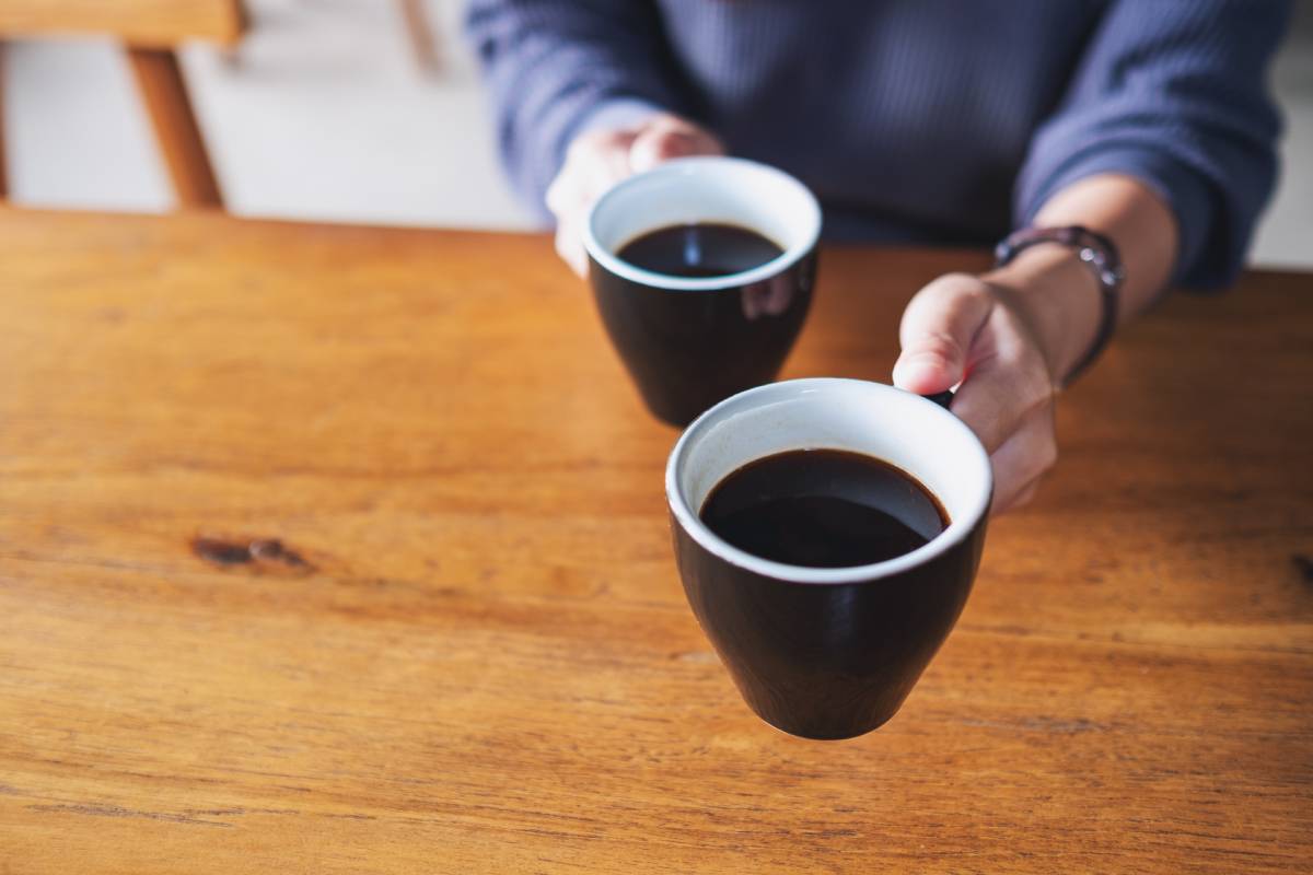 Closeup image of a woman holding and serving two cups of coffee
