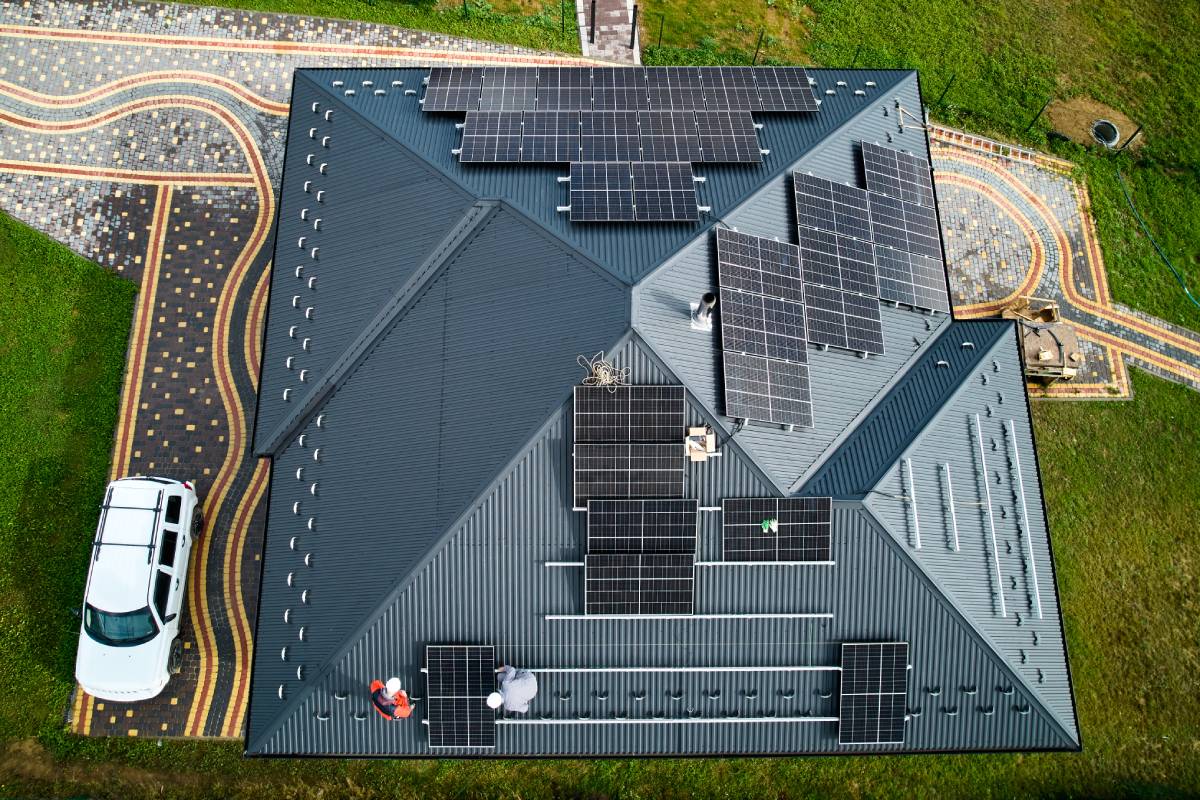 Men workers installing solar panels on roof of house.