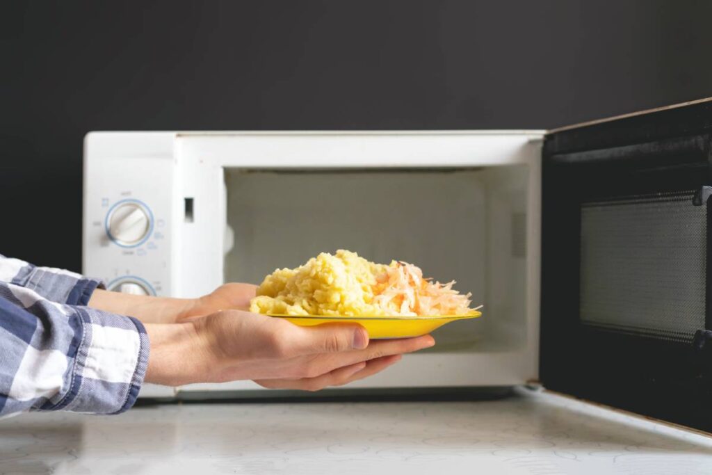 closeup photo of man use microvave oven to heat the food