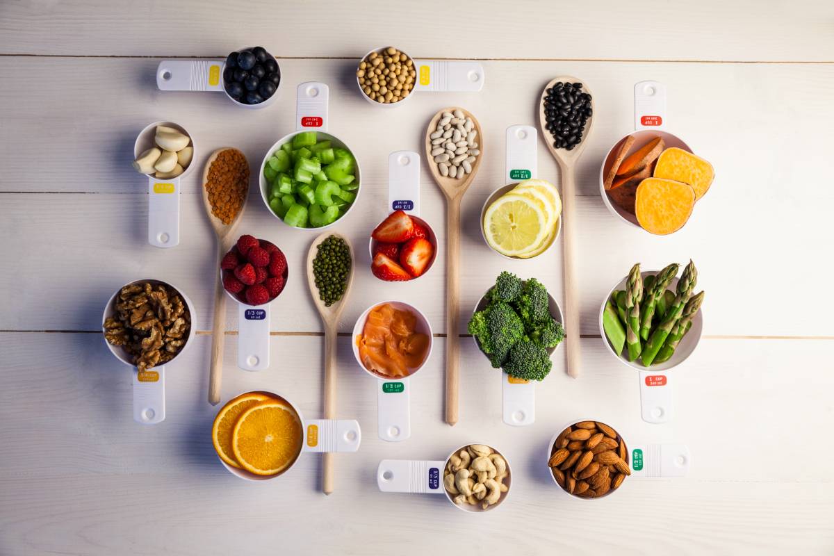 Portion cups and spoons of healthy ingredients on wooden table