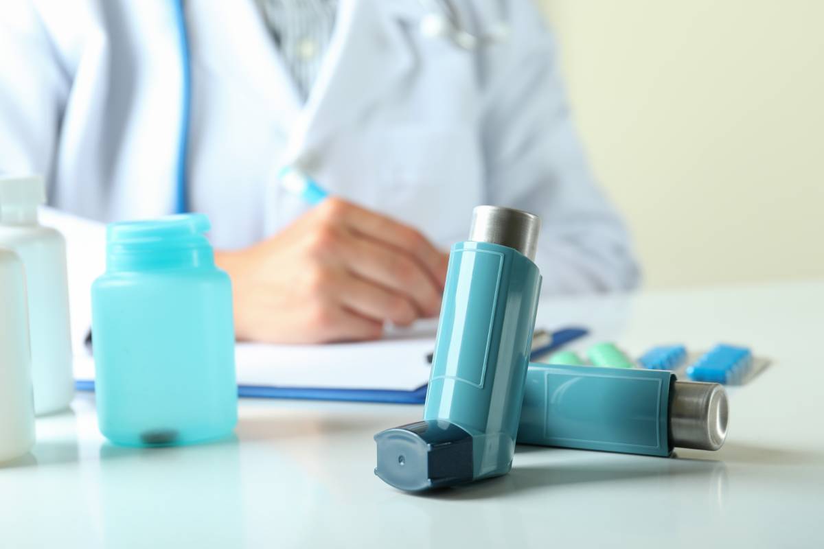 Inhaler against female doctor sitting at the table and writing