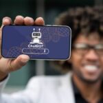 Positive african american entrepreneur showing phone with chatbot