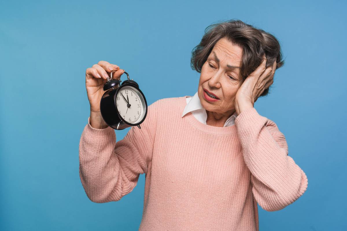 Deadline! Hurry up! Scared mature woman holding alarm clock watch feeling shock isolated.