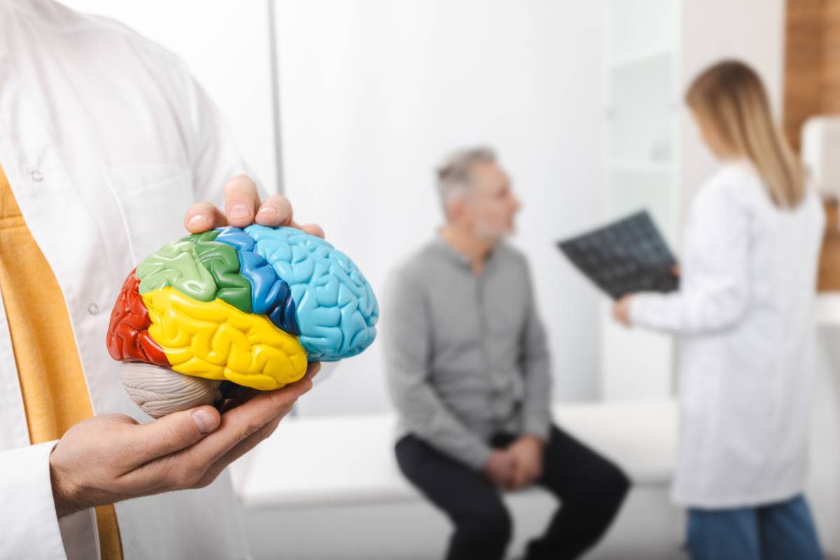 Man with migraine and headache at consultation with neurologist who is looking at MRA of patient's head to analyze his brain health. MRI diagnostics